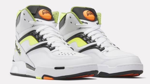 Side view of white, black, and yellow Reebok shoes.